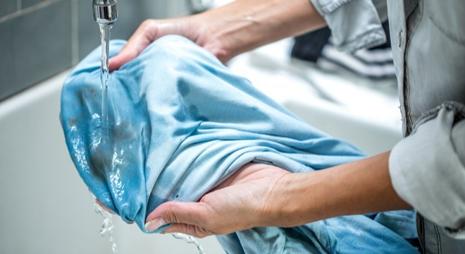 یک لباس آبی رنگ در دستان یک زن - پاک کردن لکه مام روی لباس