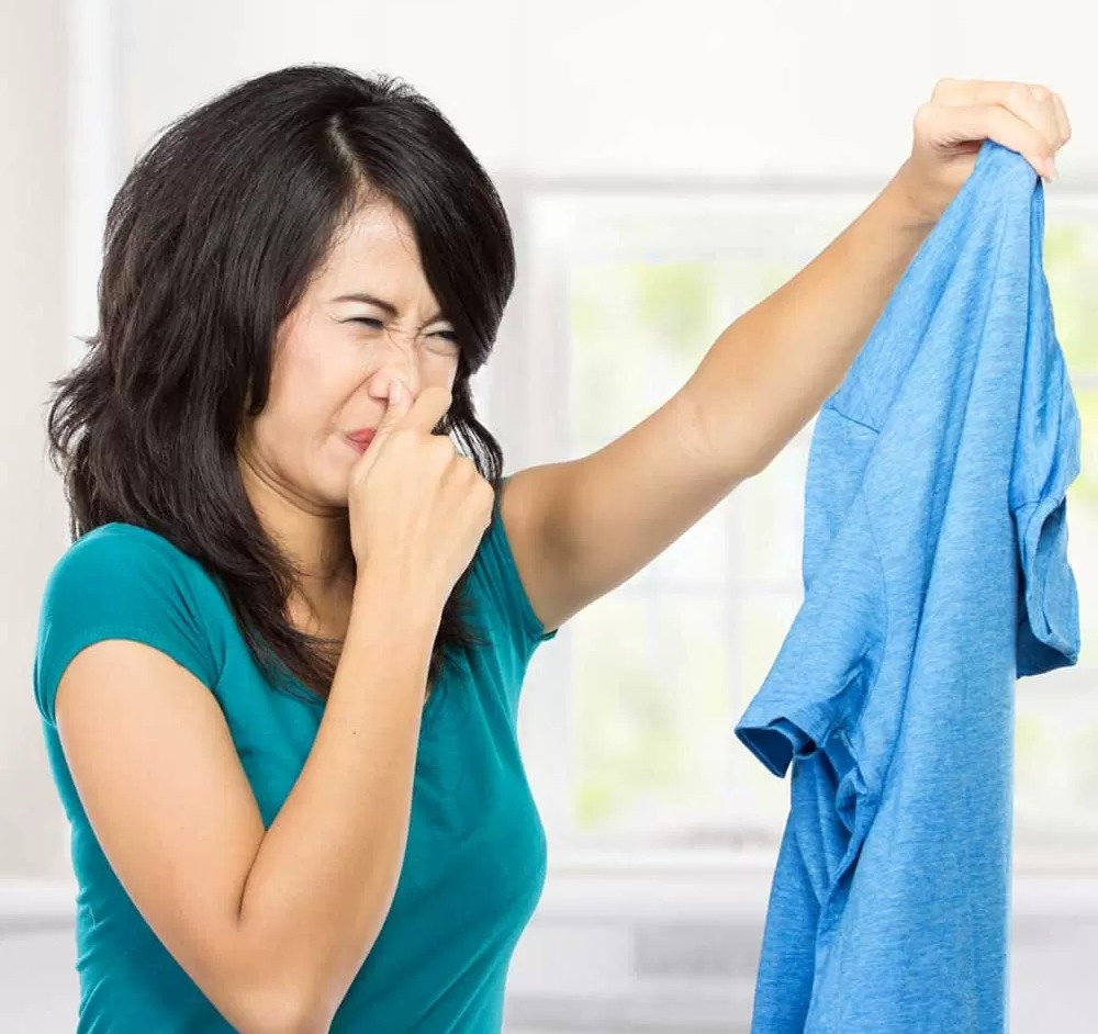 زن مشمئز شده از بوی لباس - رفع بوی دود از لباس